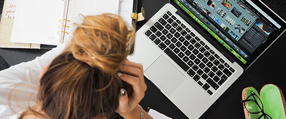 Frustrated Millennial woman with head in her hands trying to file taxes